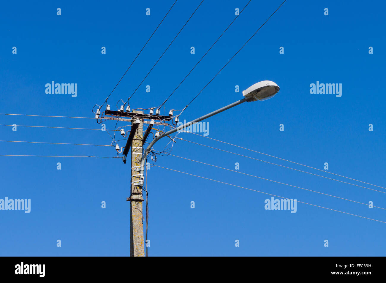 Lampadaire avec de nombreux fils électriques contre le ciel bleu Banque D'Images