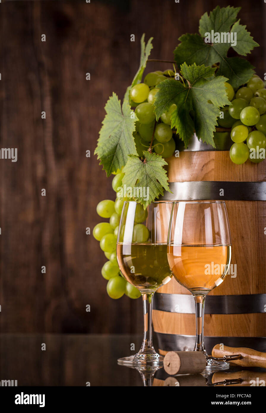 Verres de vin avec le baril et les raisins et fond en bois foncé Banque D'Images