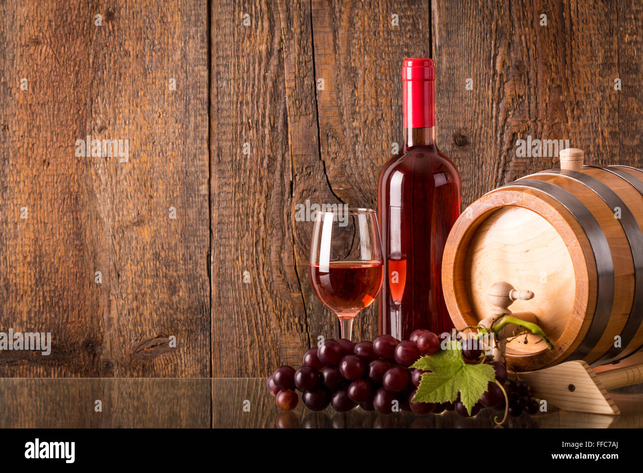 Verre de vin rose avec baril bouteille raisin et fond de bois Banque D'Images