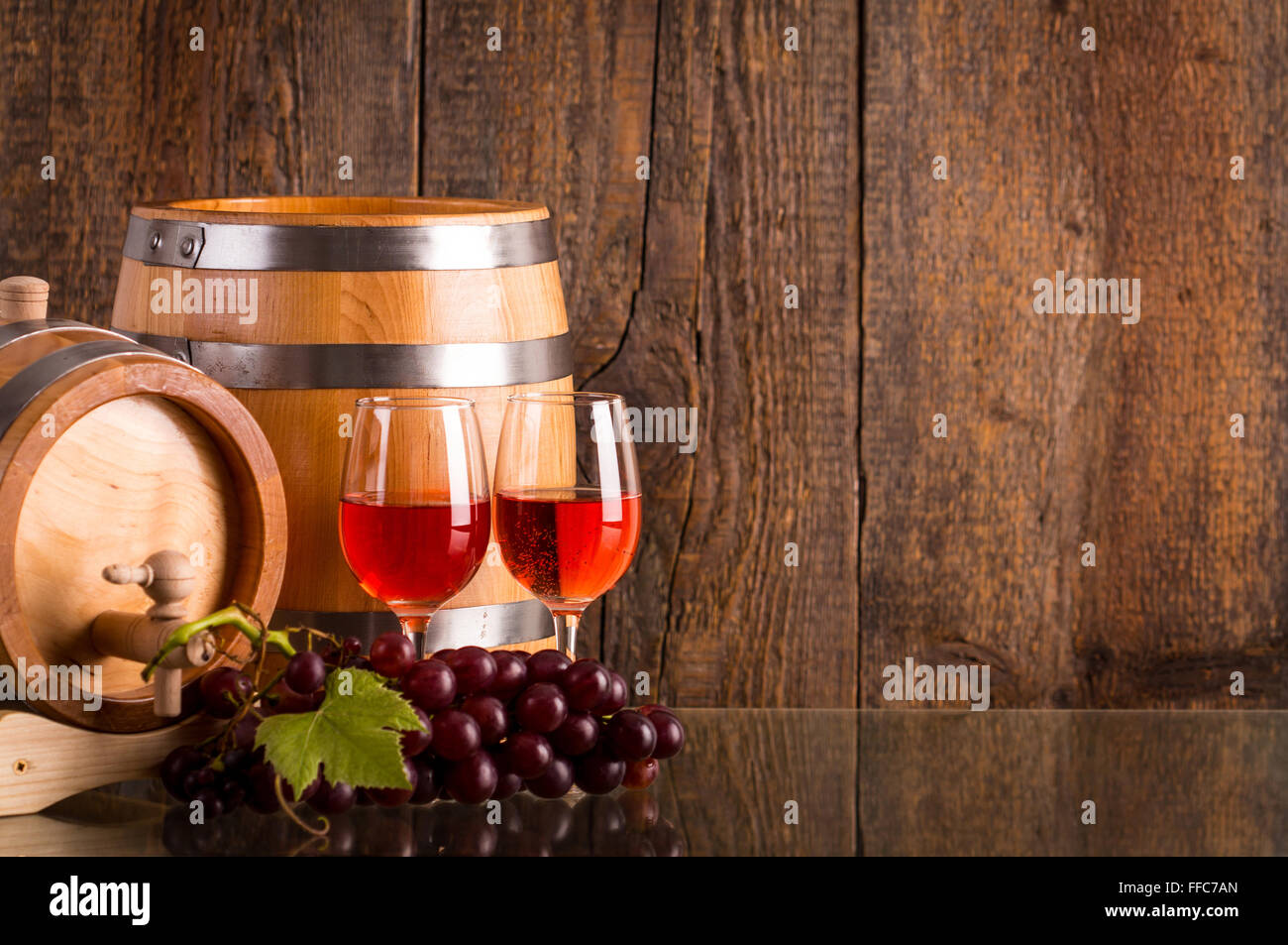 Verres de vin rosé avec deux barils en bois foncé et raisins background Banque D'Images