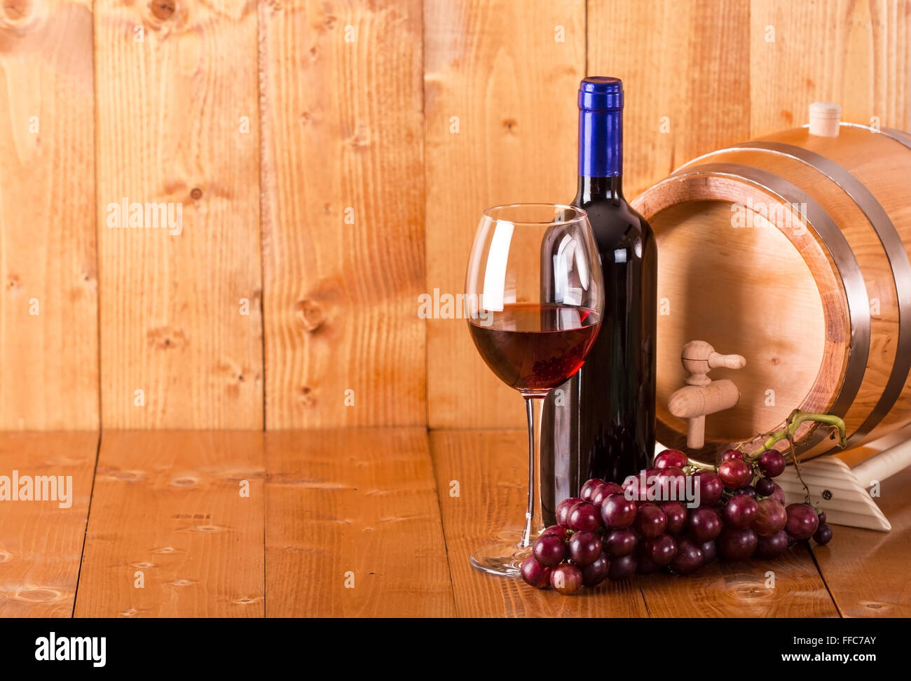 Verre de vin rouge bouteille baril et raisins sur fond de bois Banque D'Images