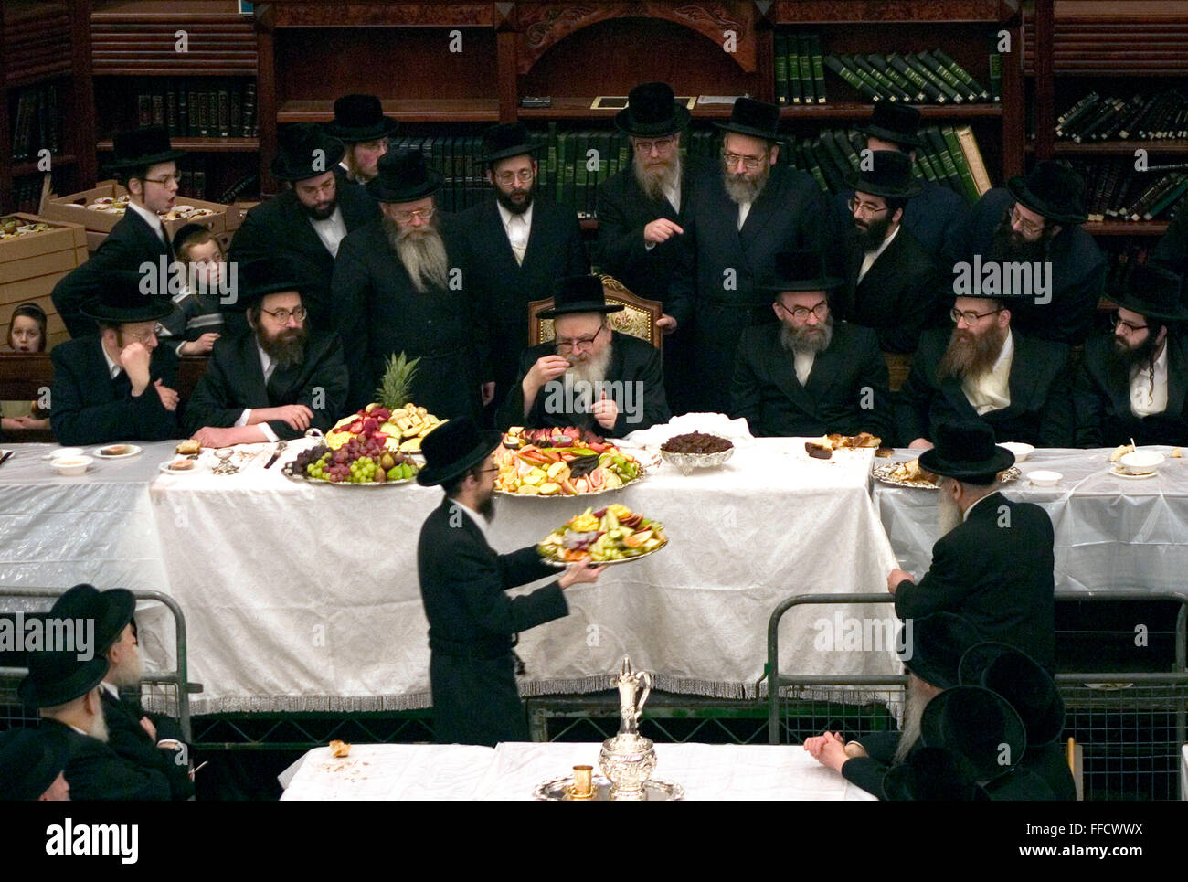 Le Juif orthodoxe de Tu Bishvat festival est célébré comme le Nouvel An des arbres avec un repas symbolique de différentes variétés de fruits. Ici dans une synagogue Stamford Hill la Skver 'hassidique Rabbi en visite de New York bénit les fruits en face de l'ensemble de la synagogue. Banque D'Images