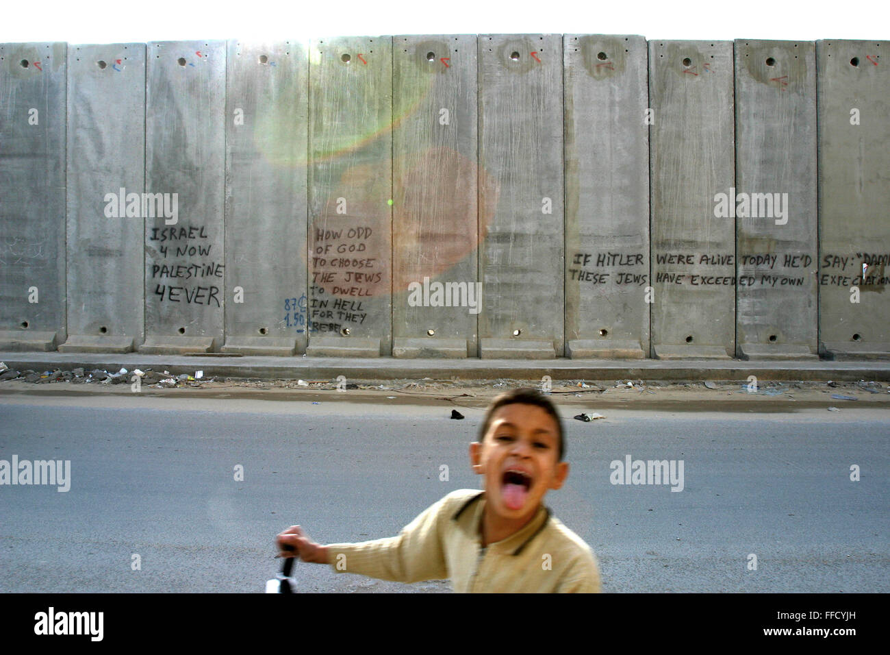 Un jeune garçon palestinien devant le mur. Des déclarations politiques sont communs decoration le long du mur construit par les Israéliens pour séparer la Palestine et Israël. Banque D'Images