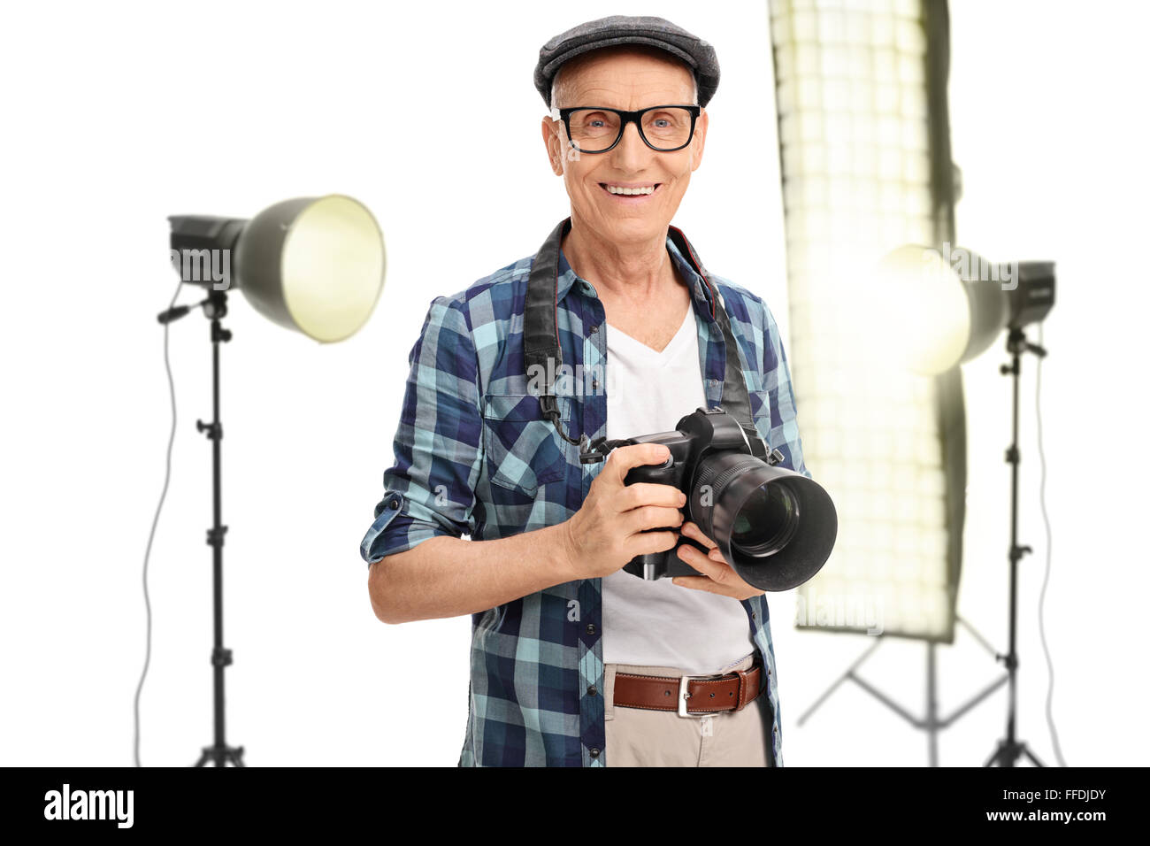 Photographe senior debout dans un studio avec des lampes studio derrière lui isolé sur fond blanc Banque D'Images