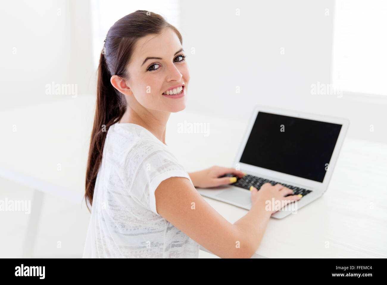 Happy teen girl using laptop computer at home Banque D'Images