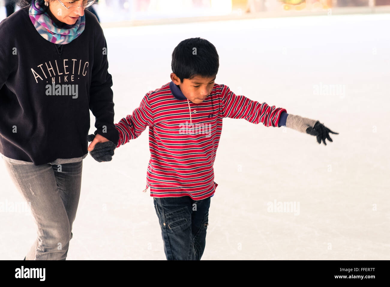 Florence, Italie. Femme mûre blanche avec son garçon adopté latine patinage sur glace. La saison d'hiver Banque D'Images