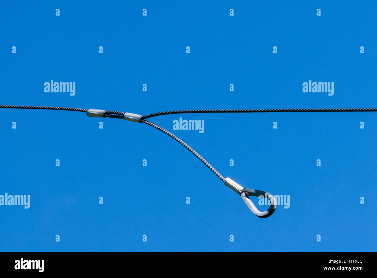 Seul le câble de métal mince avec une boucle pendant vers le bas contre le ciel bleu clair. Banque D'Images