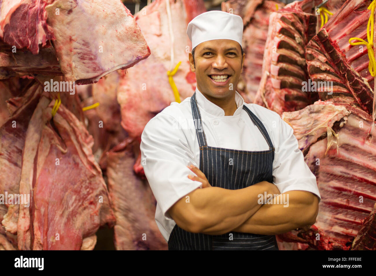 Heureux mâle mature butcher debout dans la salle de stockage de la boucherie Banque D'Images