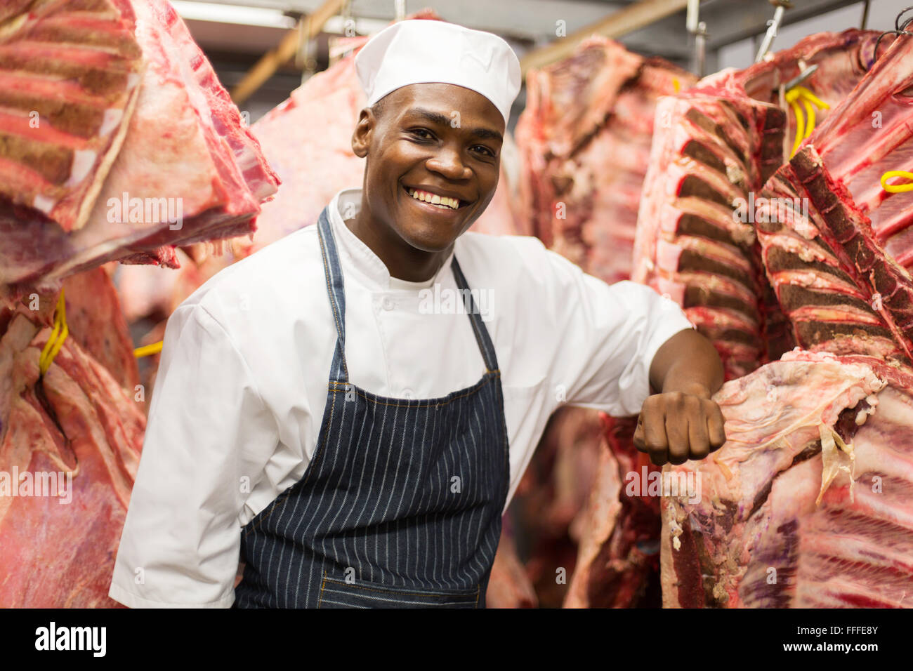 Certains hommes africains butcher debout près de viande suspendues Banque D'Images