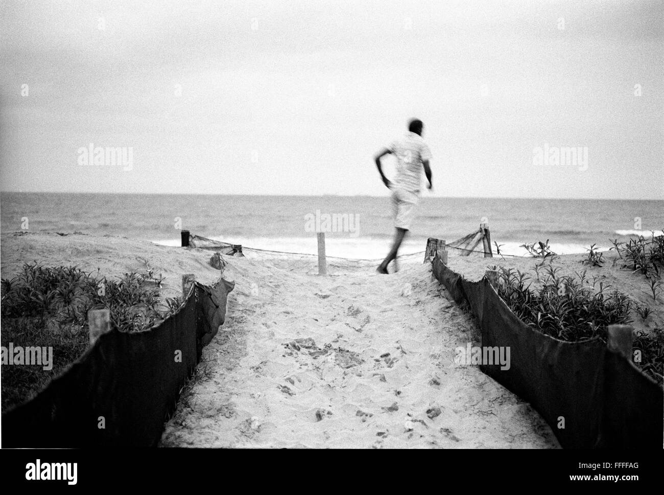 Jan 4, 2016 - South Beach, KwaZulu-Natal, Afrique du Sud - Un homme qui marche à travers les dunes sur South Beach. South Beach est une partie de la ville de Durban sans interruption la plus longue étendue de plage de sable. La ville de Durban est sur la côte est de l'Afrique du Sud et les gens ici sont lavés avec de l'eaux chaudes de l'Océan Indien. Au nord de cette étendue de sable sont des plages avec la société hang out cafe. Au sud il y a une jetée avec le quartier haut Moyo's Restaurant à elle est la fin et l'uShaka Marine World et le secteur complexe de la mer et surf clubs de la plage les vesces. Entre ces n Banque D'Images