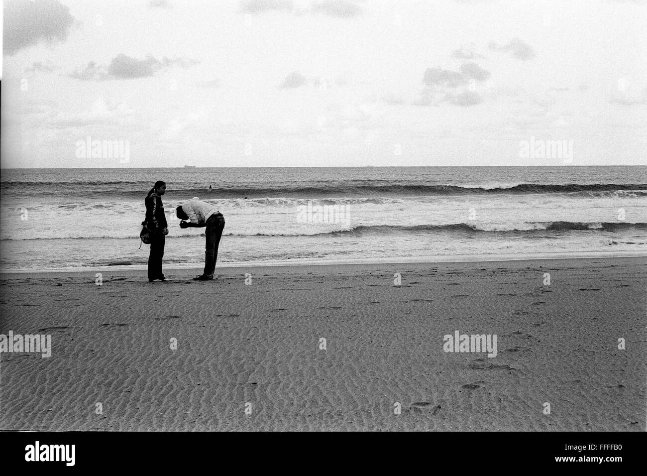 Jan 4, 2016 - South Beach, KwaZulu-Natal, Afrique du Sud - Deux jeunes amants d'allumer une cigarette dans la lumière du soir. South Beach est une partie de la ville de Durban sans interruption la plus longue étendue de plage de sable. La ville de Durban est sur la côte est de l'Afrique du Sud et les gens ici sont lavés avec de l'eaux chaudes de l'Océan Indien. Au nord de cette étendue de sable sont des plages avec la société hang out cafe. Au sud il y a une jetée avec le quartier haut Moyo's Restaurant à elle est la fin et l'uShaka Marine World et le secteur complexe de la mer et surf clubs de la plage les vesces. Entre Banque D'Images