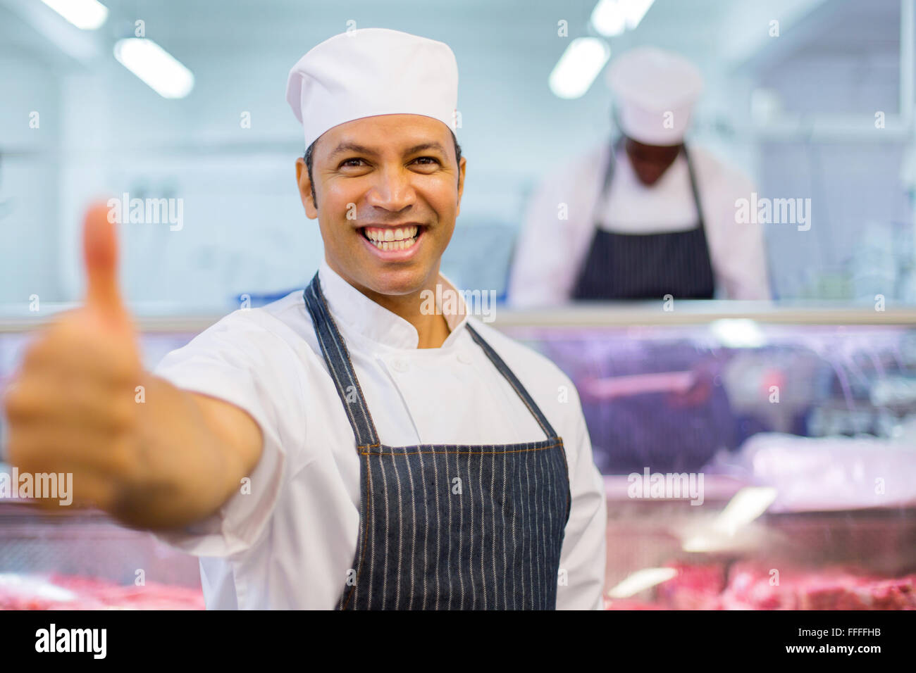 Cheerful male butcher thumb up en boucherie Banque D'Images