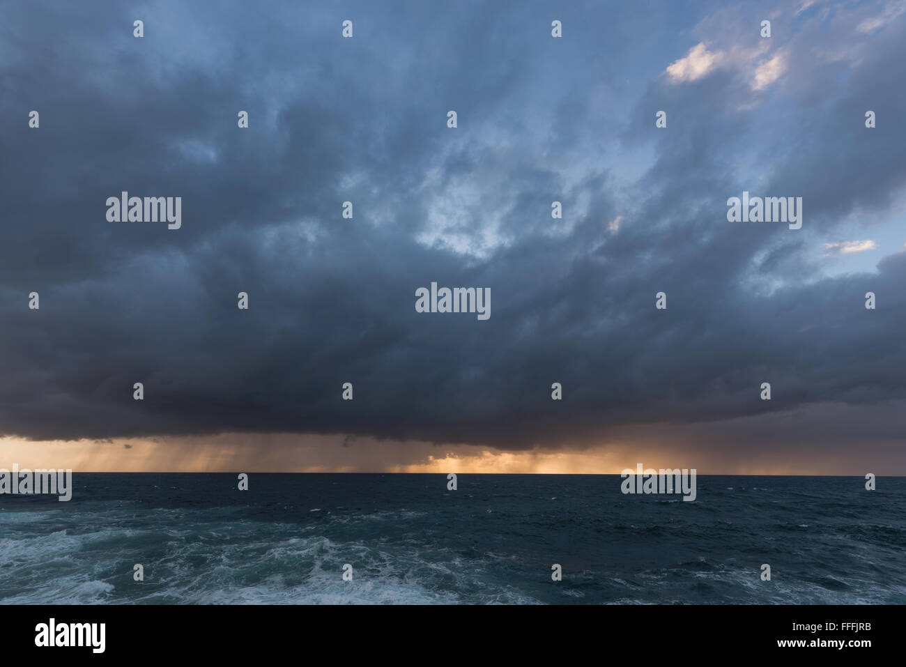 Approche de l'orage avec pluie nuages sur la mer au lever du soleil Banque D'Images