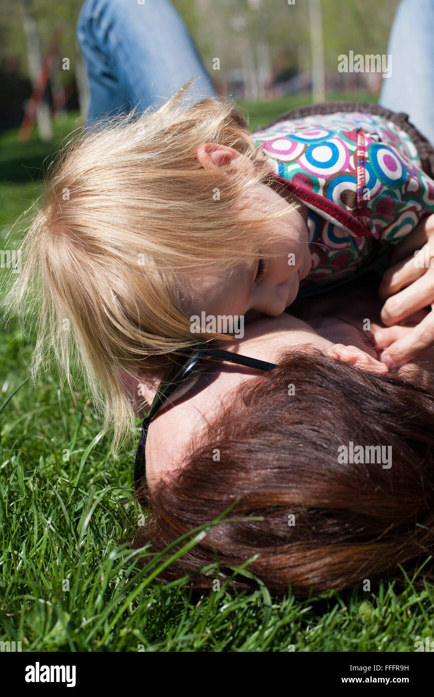 Deux Ans De Chemise De Couleur Blond Bebe Serrant Avec Brunette Woman Mere Avec Lunettes Noir Couche Sur La Pelouse De L Herbe Verte Photo Stock Alamy