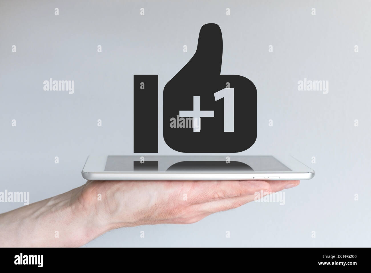 Réseau social Thumbs up icône avec signe plus. Concept de l'informatique mobile et les médias sociaux. Main tenant une tablette ou un téléphone intelligent. Banque D'Images