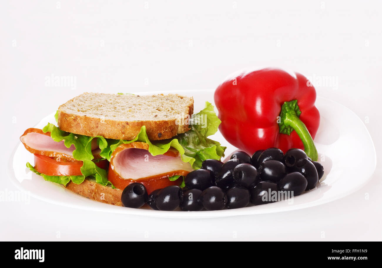 Gros sandwich sain avec pain complet, jambon, tomates, poivre, d'olive et la laitue frisée sur la plaque. Banque D'Images