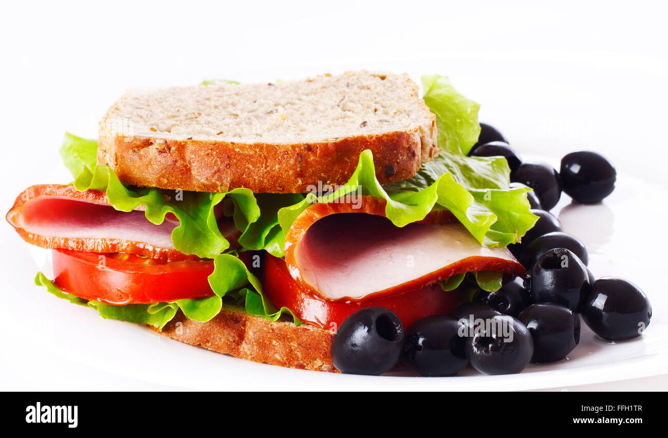 Gros sandwich sain avec pain complet, jambon, tomates, laitue frisée et olive sur la plaque. Banque D'Images