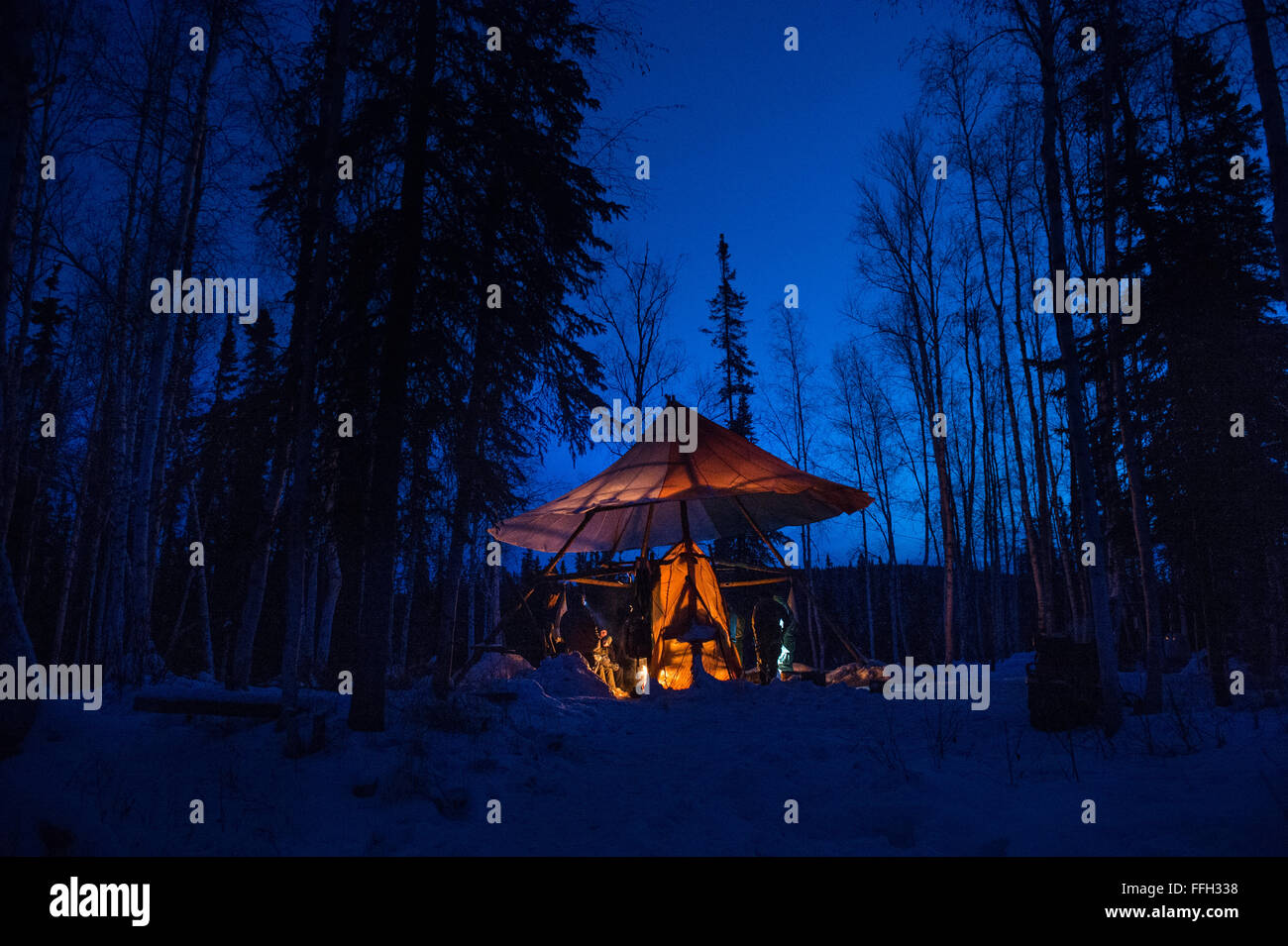 La survie dans l'Arctique, U.S. Air Force les étudiants de l'École s'asseoir autour d'un feu et de discuter de leur formation avant la tombée de la nuit. Les professeurs enseignent dans les deux conditions de jour que de nuit pour simuler un scénario de survivant. Banque D'Images