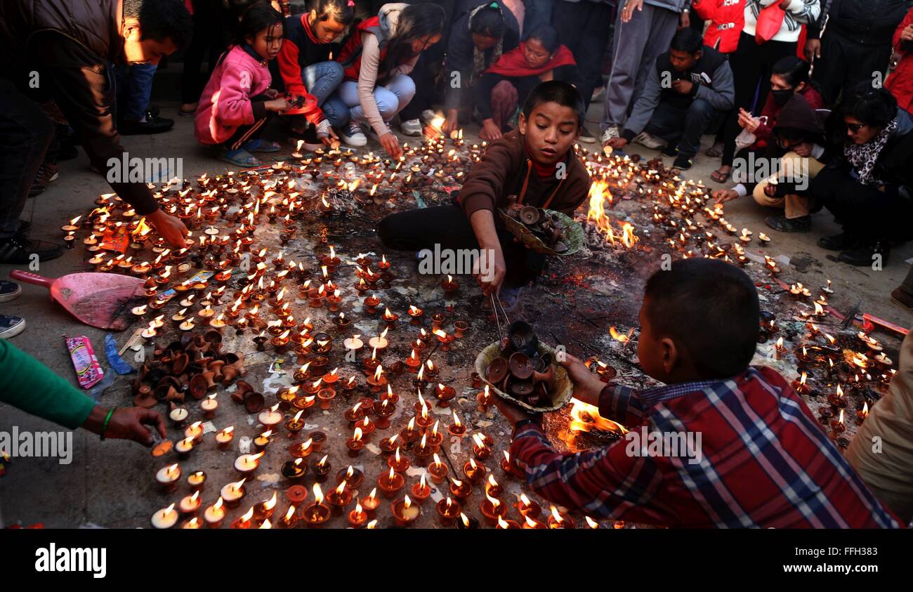 Katmandou, Népal. Feb 13, 2016. Garçon népalais recueille des lampes à beurre tandis que d'autres offrent des prières dans les locaux de Saraswati temple pendant Shree Panchami Festival à Katmandou, Népal, 10 févr. 13, 2016. Communauté hindoue népalais célèbre ce jour comme le jour de l'adoration de la Déesse de la connaissance, Saraswati. Les élèves montrent leur humble respect à la Déesse Saraswati pour la connaissance et l'apprentissage. Ce jour signifie aussi que le début de saison du printemps. Credit : Sunil Sharma/Xinhua/Alamy Live News Banque D'Images