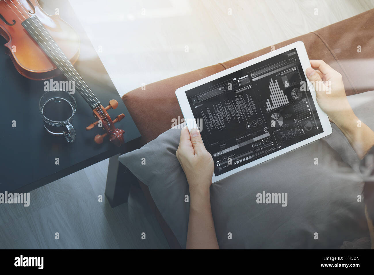 Hipster part composer la musique avec tablette numérique compter et sitting on sofa at home studio Banque D'Images