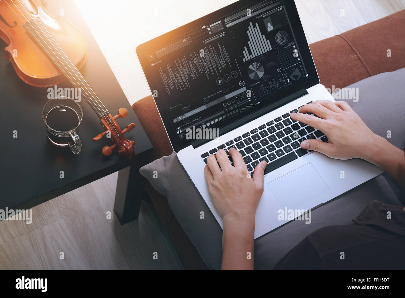 Hipster part composer de la musique avec ordinateur portable compter et sitting on sofa at home studio Banque D'Images