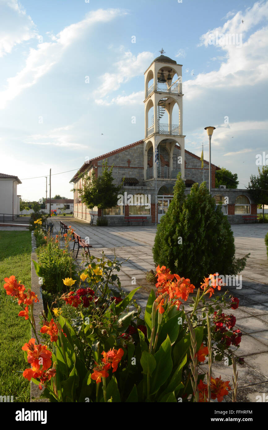Église grecque dans le village de Chrysohorafa, Grèce du Nord avec des fleurs colorées en premier plan Banque D'Images