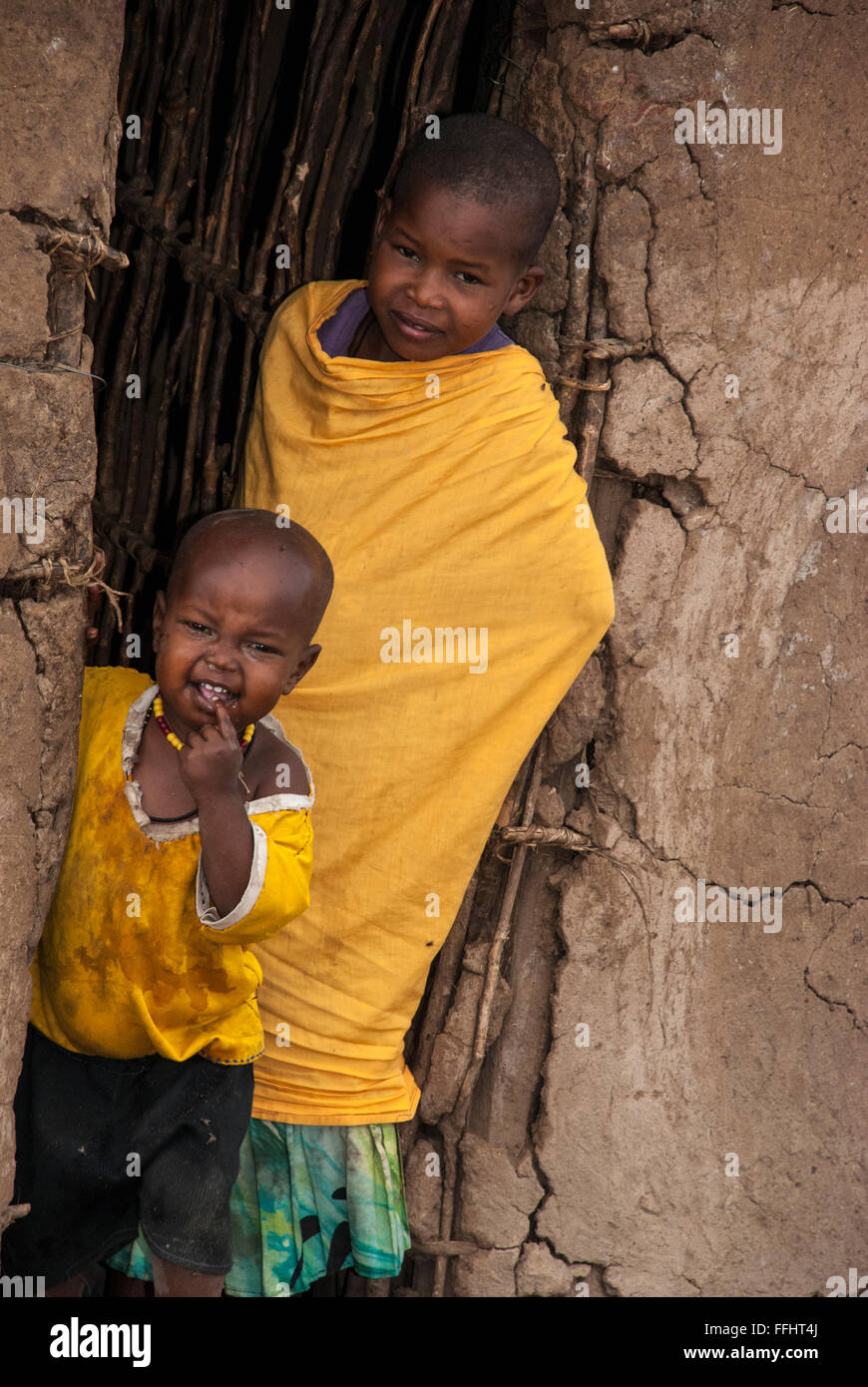 Deux enfants Masai dans l'embrasure d'une hutte de terre dans un village de la Masai Mara, Kenya, Afrique Banque D'Images