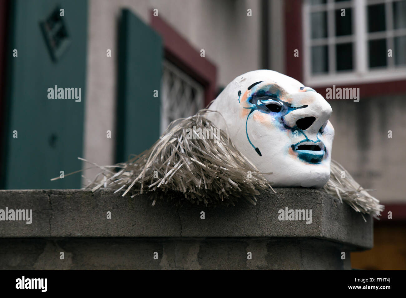 Un seul masque du carnaval de Bâle 2015 reposant sur un mur près d'une maison, en attente de son propriétaire. Banque D'Images