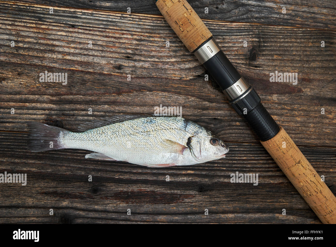 Canne, moulinet et le poisson isolé sur fond de bois, vue du dessus Banque D'Images