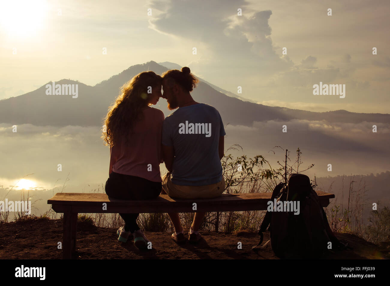 Vue arrière d'un couple aimant profiter du coucher du soleil à le soleil au sommet de la montagne. Le point de droit. Banque D'Images