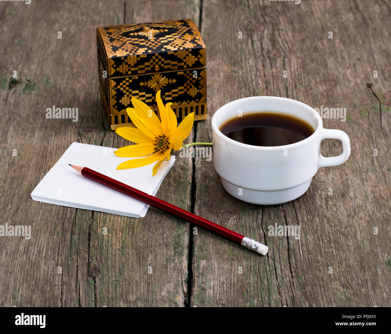 Crayon, café et le cercueil orné d'une fleur jaune Banque D'Images