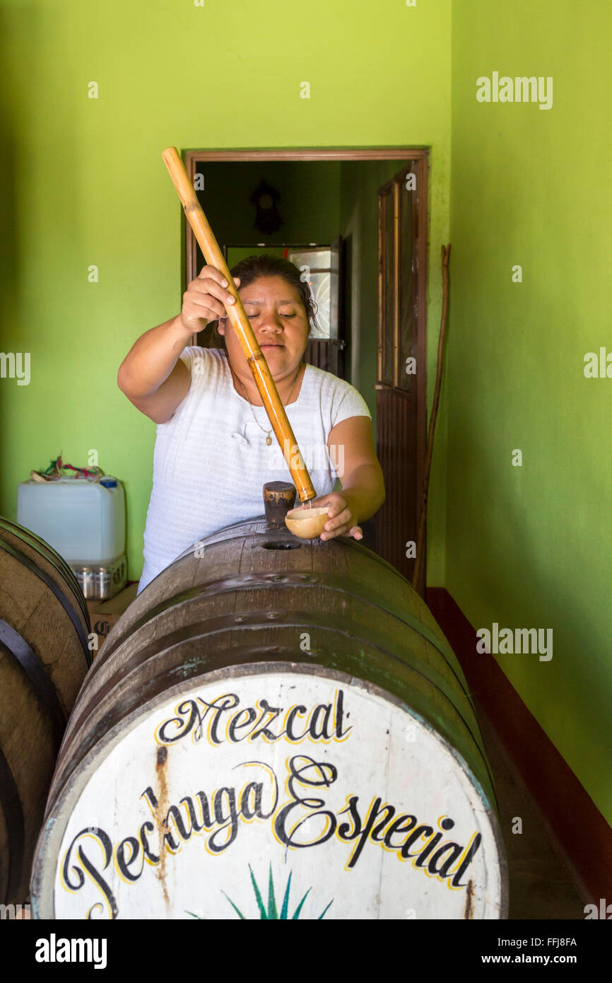 Matatlán Santiago, Oaxaca, Mexique - en une distillerie de Mezcal, une femme prend un échantillon à partir d'un baril pour les clients au goût. Banque D'Images