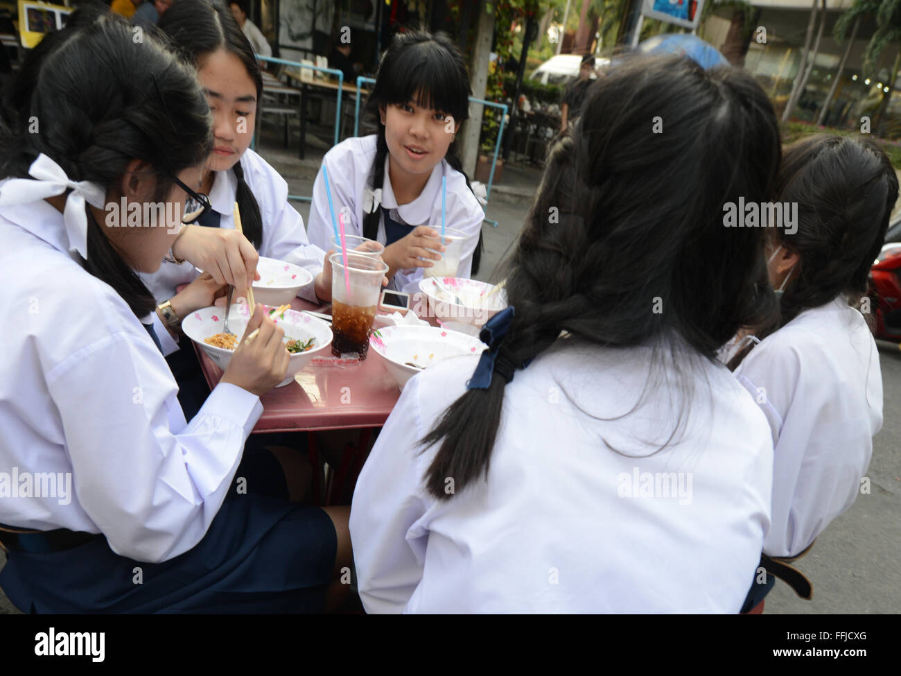 Les élèves du secondaire thaïlandais bénéficiant d''un bol de soupe thaï aux vermicelles dans un petit restaurant de rue à Bangkok. Banque D'Images