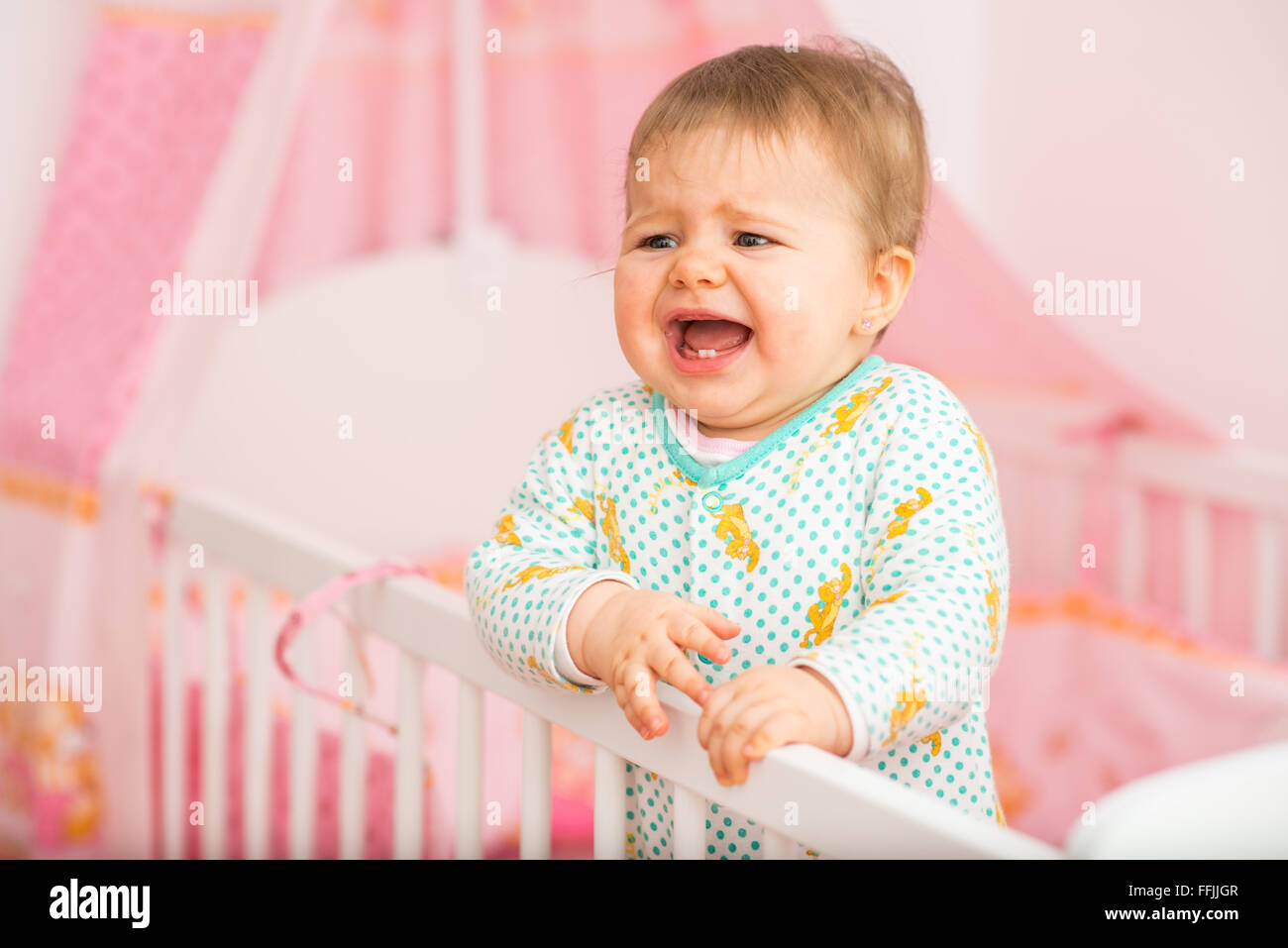 Baby Girl est juste pleurer dans le lit dans la chambre de bébé Banque D'Images