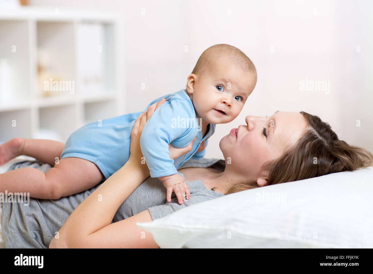 La mère et l'enfant rire et jouer lying on bed Banque D'Images