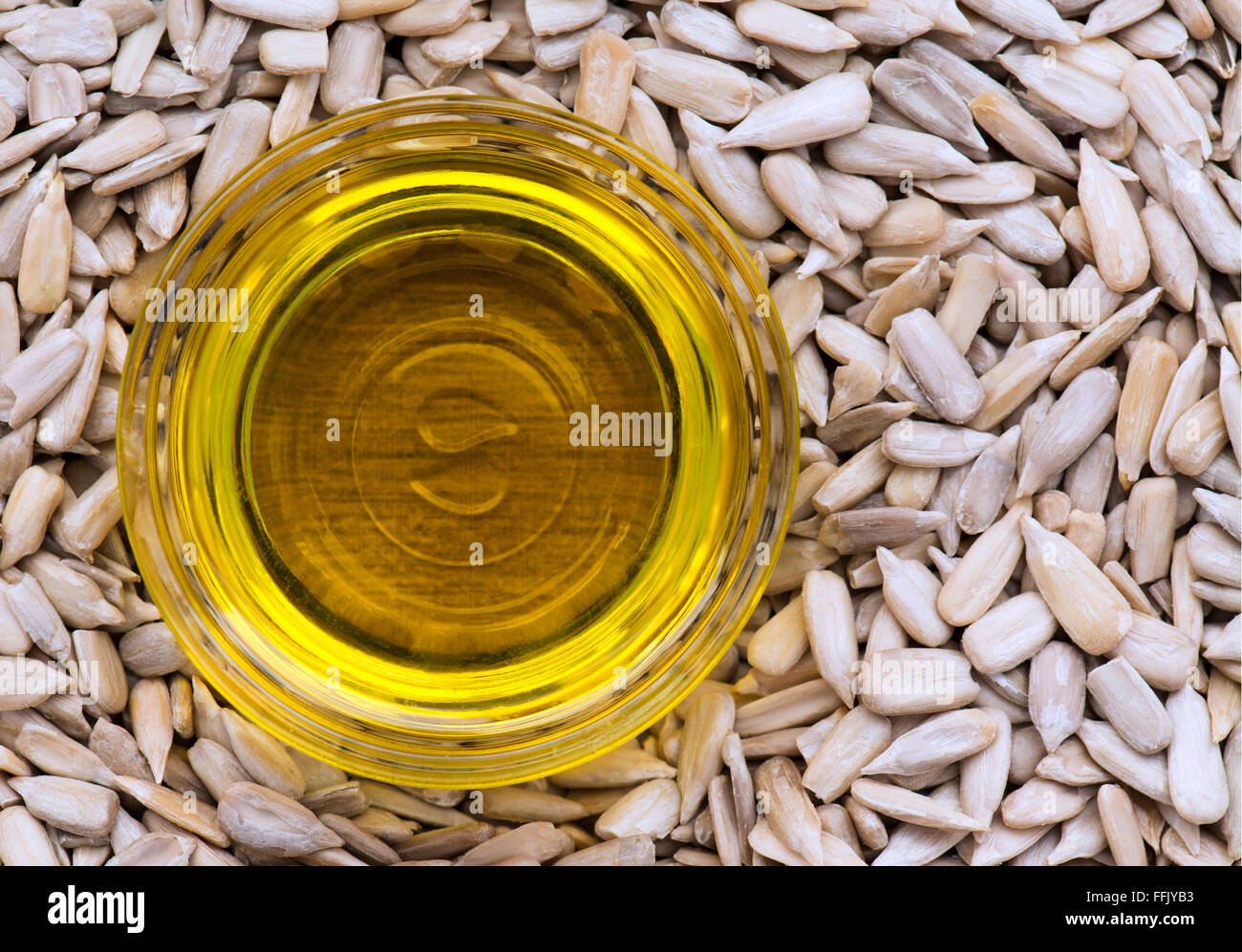 L'huile de tournesol dans un petit récipient en verre, assis dans un lit de graines de tournesol . Banque D'Images