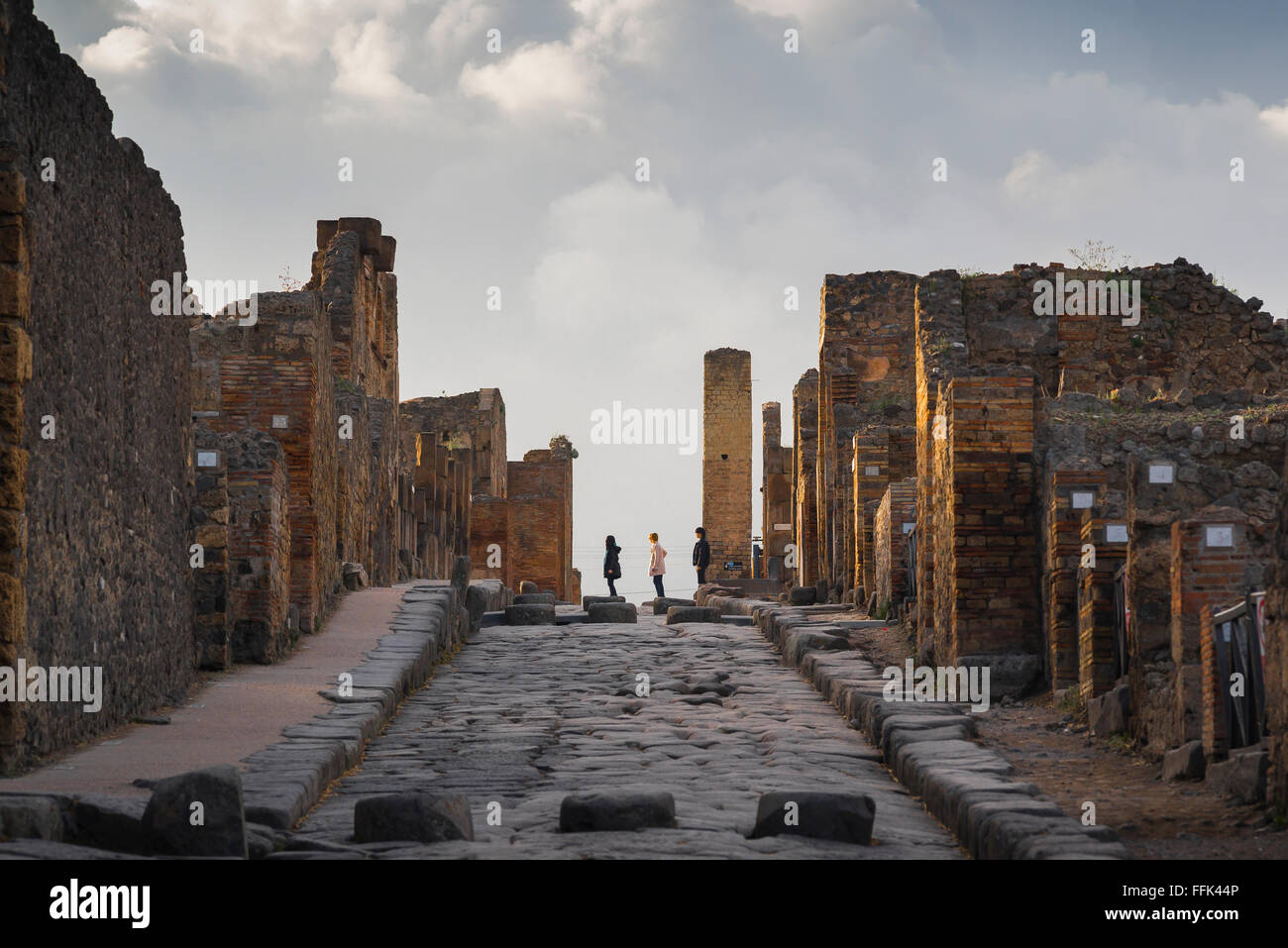 Tourisme de Pompéi, vue au coucher du soleil de trois visiteurs de l'ancienne ville de Pompéi, située dans la via dell' Abbondanza, Italie Banque D'Images