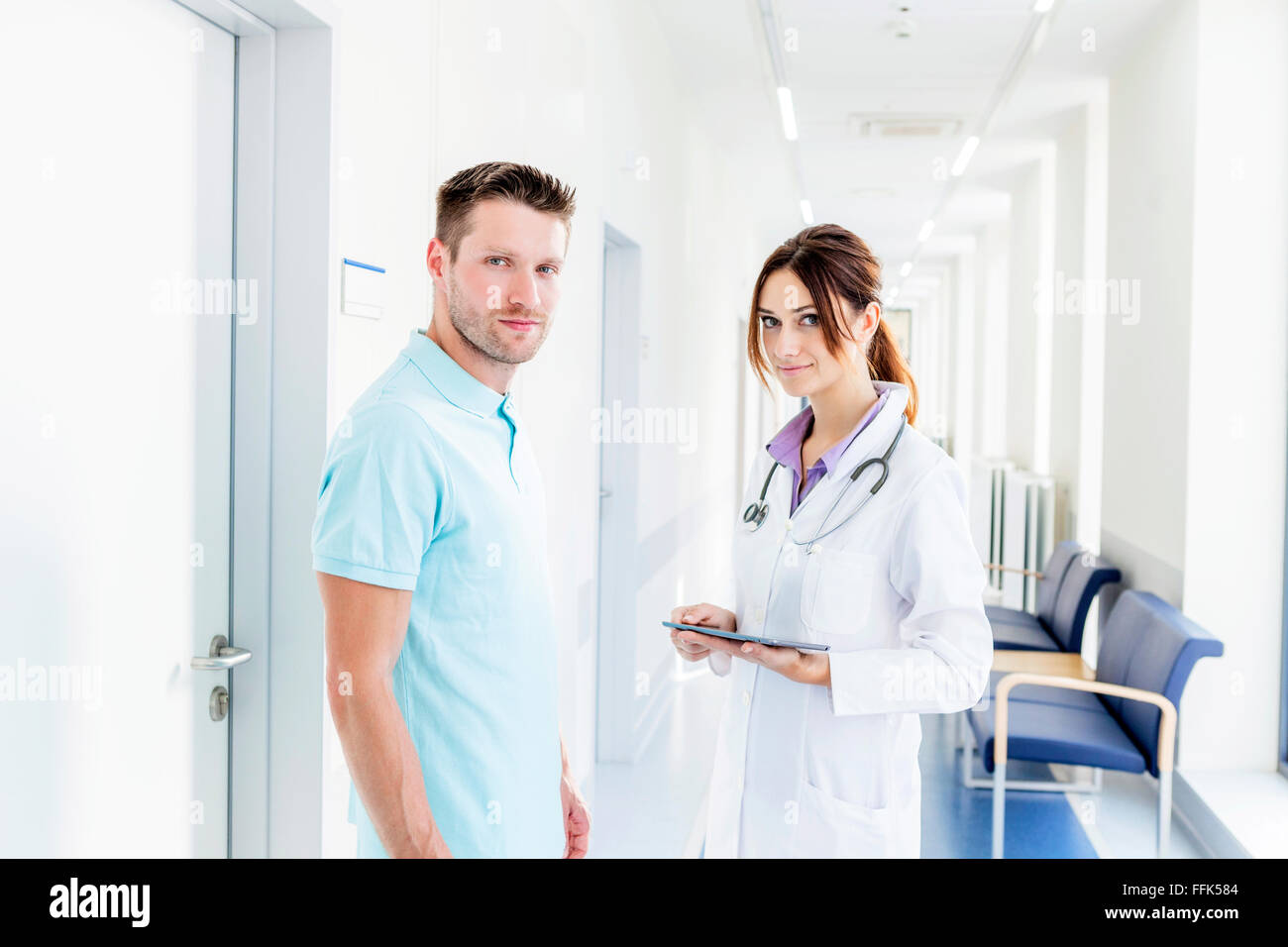 Femme médecin et collègue standing in hospital corridor Banque D'Images