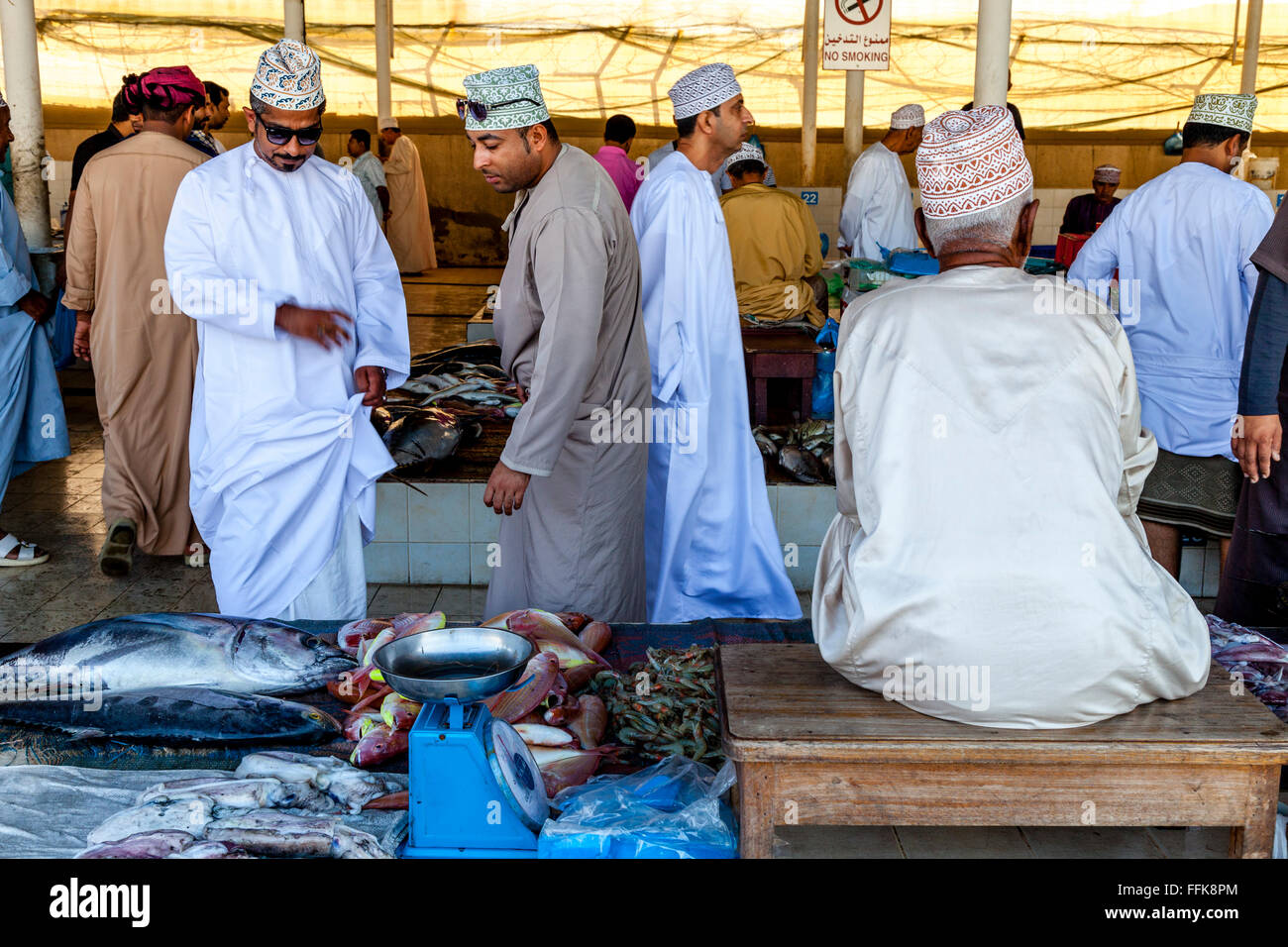 Les hommes en costume traditionnel omanais d'acheter du poisson au marché aux poissons, Muttrah, Muscat, Sultanat d'Oman Banque D'Images