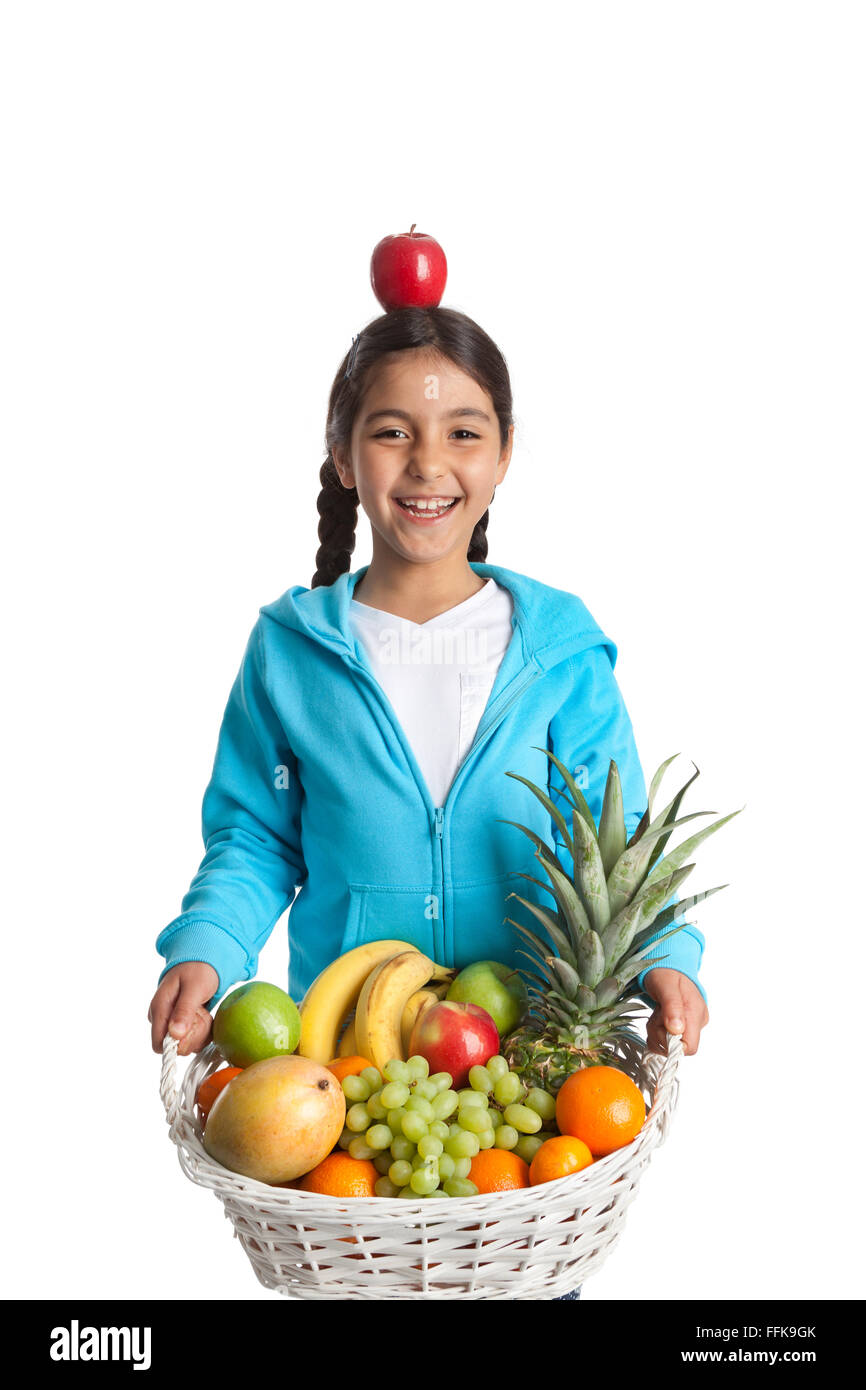 Laughing girl portant un panier de fruits avec une pomme sur sa tête sur fond blanc Banque D'Images