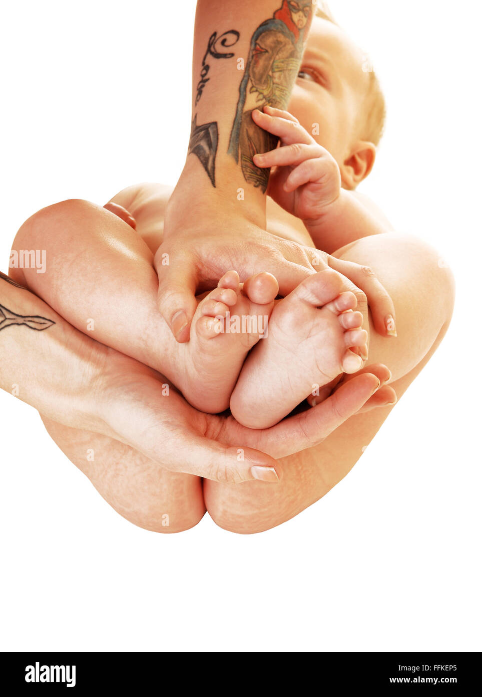Une Jeune Mere En Tatouage Sur Ses Bras Tenant Les Pieds De Son Bebe Dans Ses Mains Pour L Arriere Plan Blanc Photo Stock Alamy