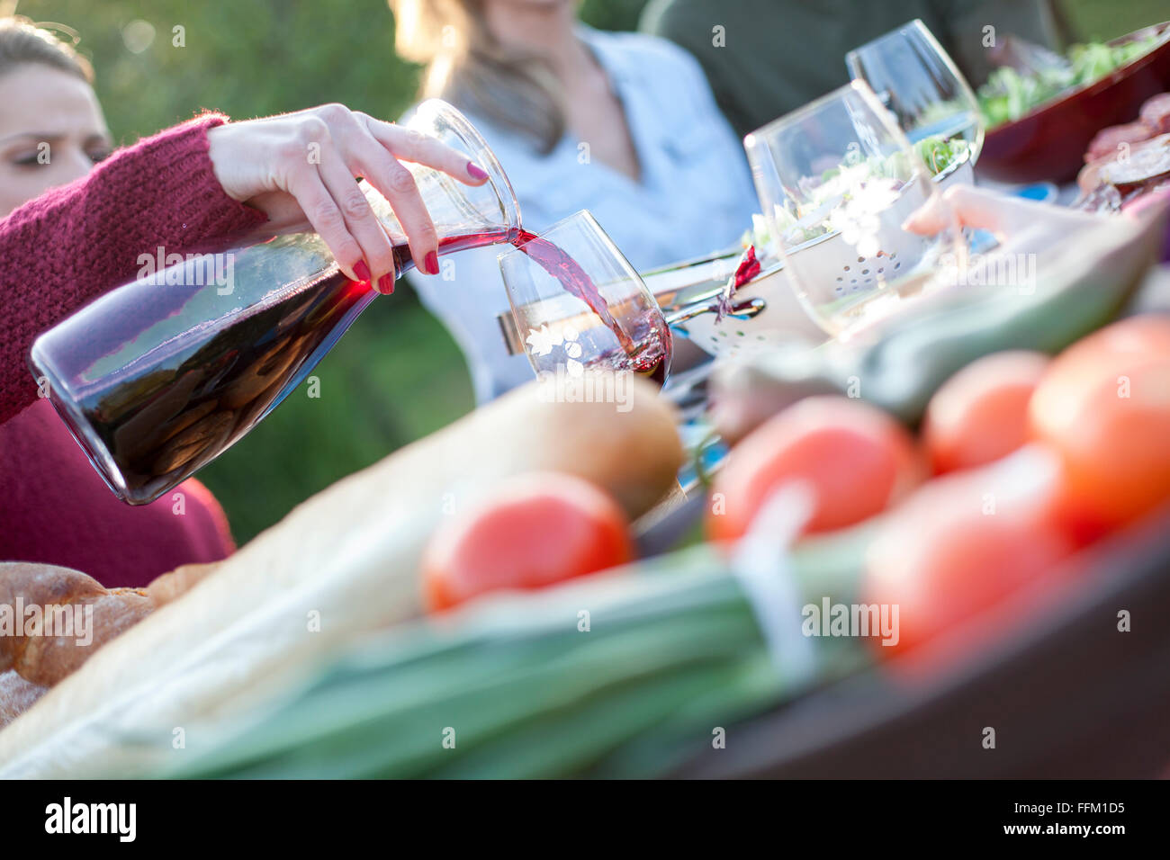 Verser le vin rouge dans un verre sur garden party Banque D'Images