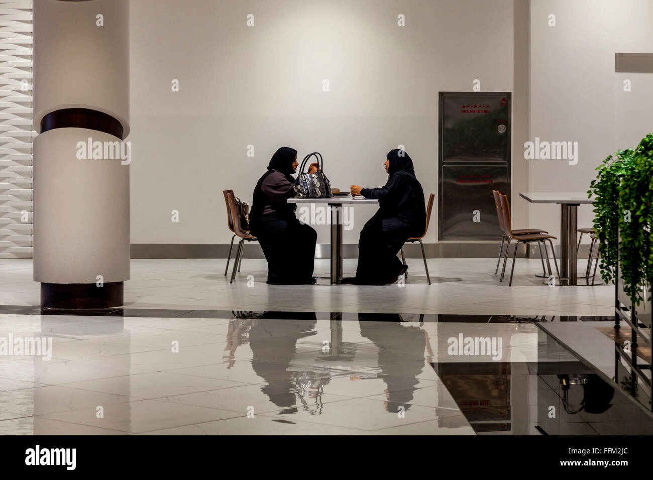 Les deux femmes en tenue traditionnelle de l'abaya assis à un café dans le centre commercial Avenues Oman, Muscat, Sultanat d'Oman Banque D'Images