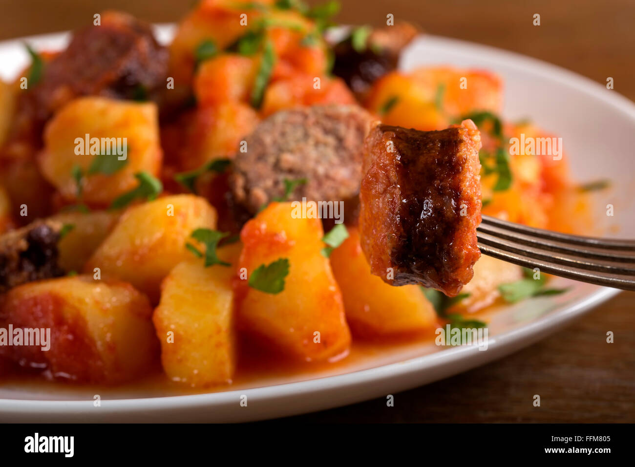Sur tranche de saucisse de pommes de terre en ragoût avec fourche en arrière-plan Banque D'Images