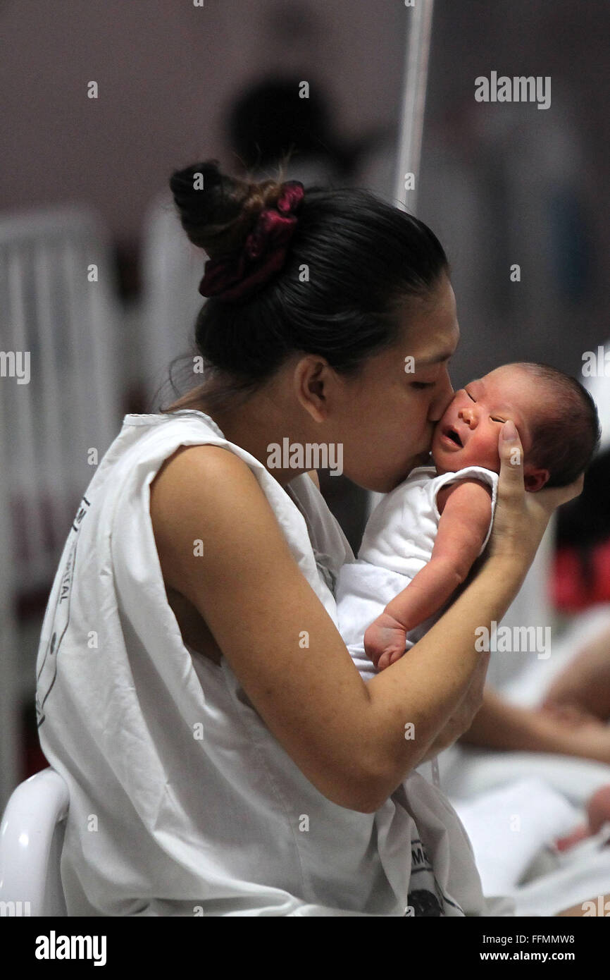 Manille, Philippines. 16 Février, 2016. Une mère embrasse son enfant nouveau-né à l'intérieur de la maternité de l'Hôpital Memorial Dr. Jose Fabella à Manille, Philippines, 16 février 2016. Le ministère philippin de la Santé a informé les femmes à ne pas tomber enceinte jusqu'à cette année on en sait davantage sur la transmission de Zika virus qui cause des anomalies des naissances en Amérique latine, en dépit du fait que les Philippines' seul cas signalé de Zika était il y a quatre ans. Credit : Rouelle Umali/Xinhua/Alamy Live News Banque D'Images