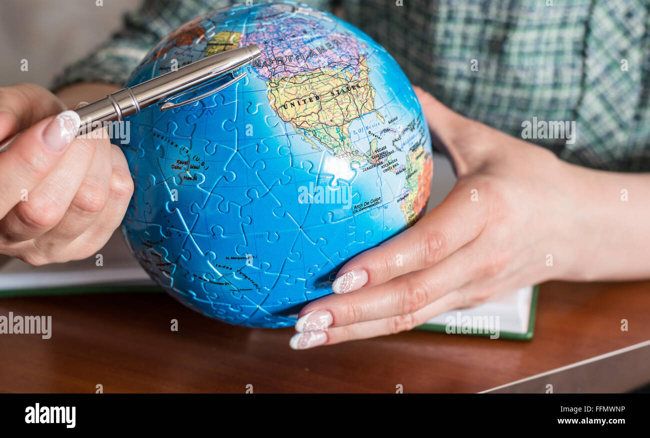 La main féminine avec un stylo et un globe du puzzle Banque D'Images