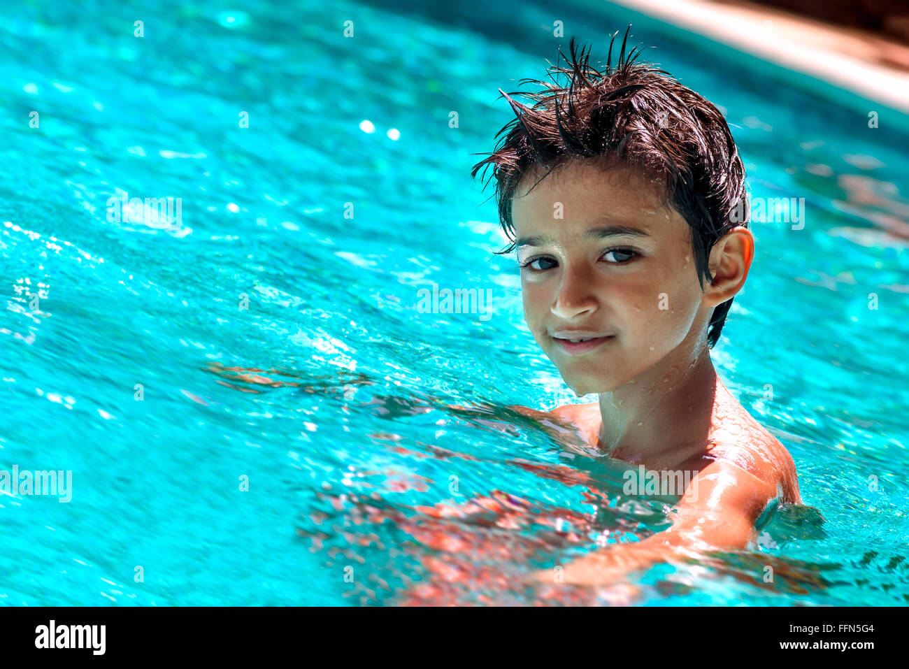 Kid garçon enfant 8 ans à l'intérieur piscine portrait heureux plaisir jour lumineux Banque D'Images