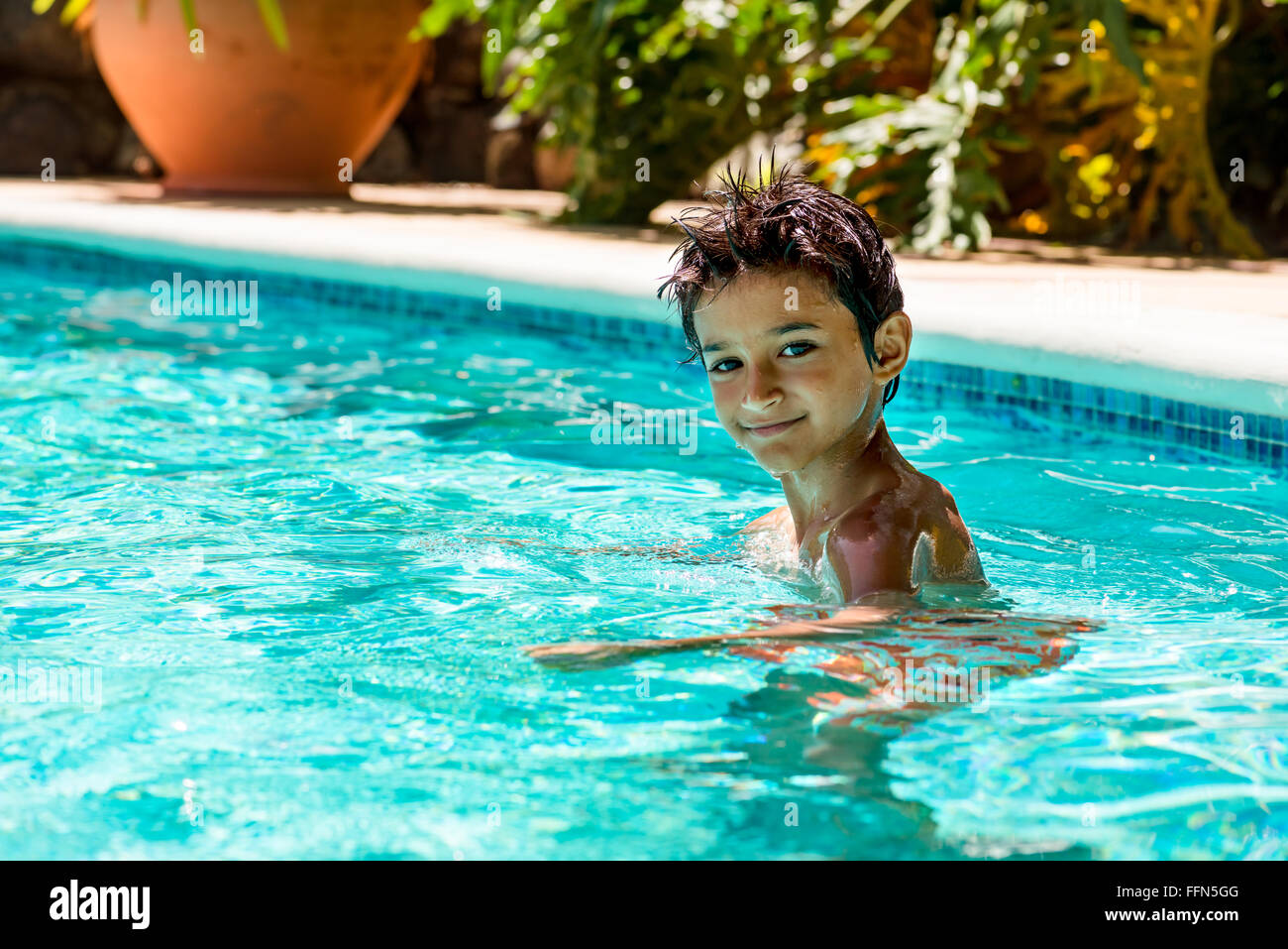 Kid garçon enfant 8 ans à l'intérieur piscine portrait heureux plaisir jour lumineux Banque D'Images