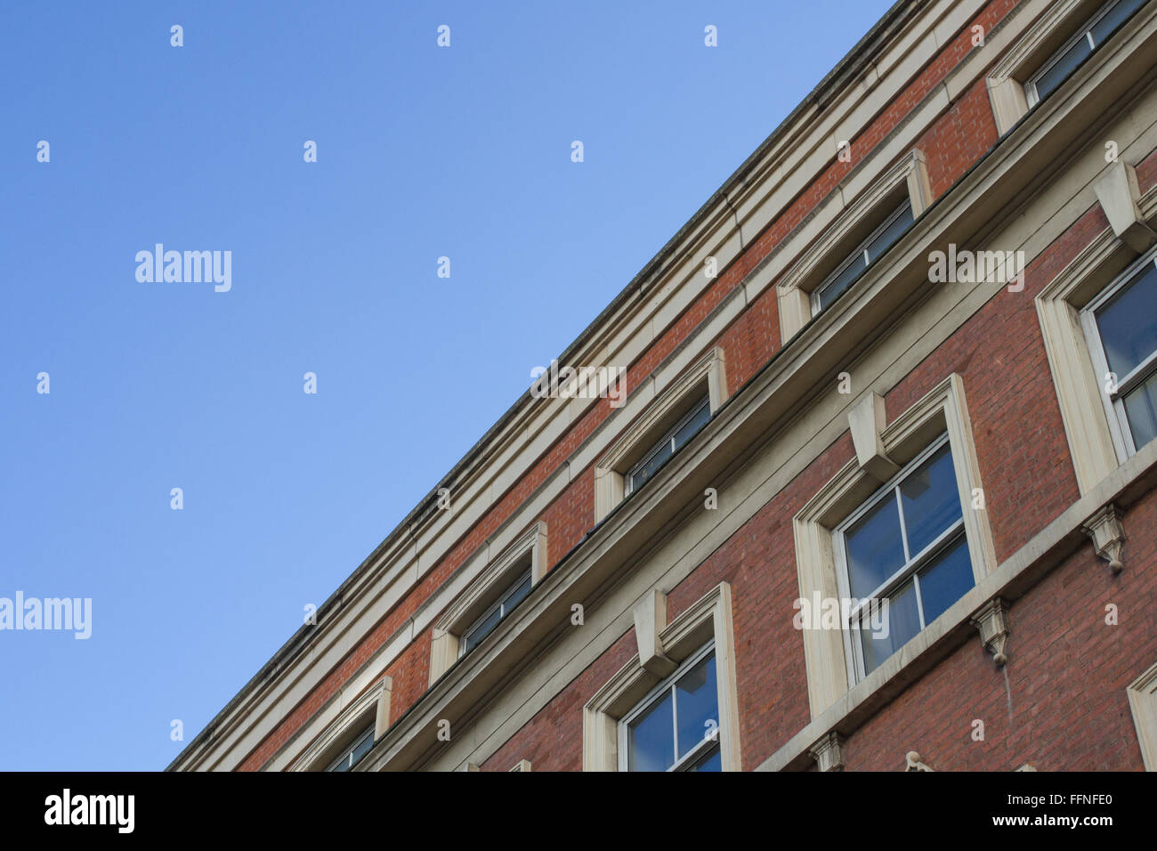 Une vue du sol à la recherche jusqu'à la toiture et de la façade d'un bâtiment d'époque, solide avec de brique rouge et de rangées de fenêtres. Banque D'Images