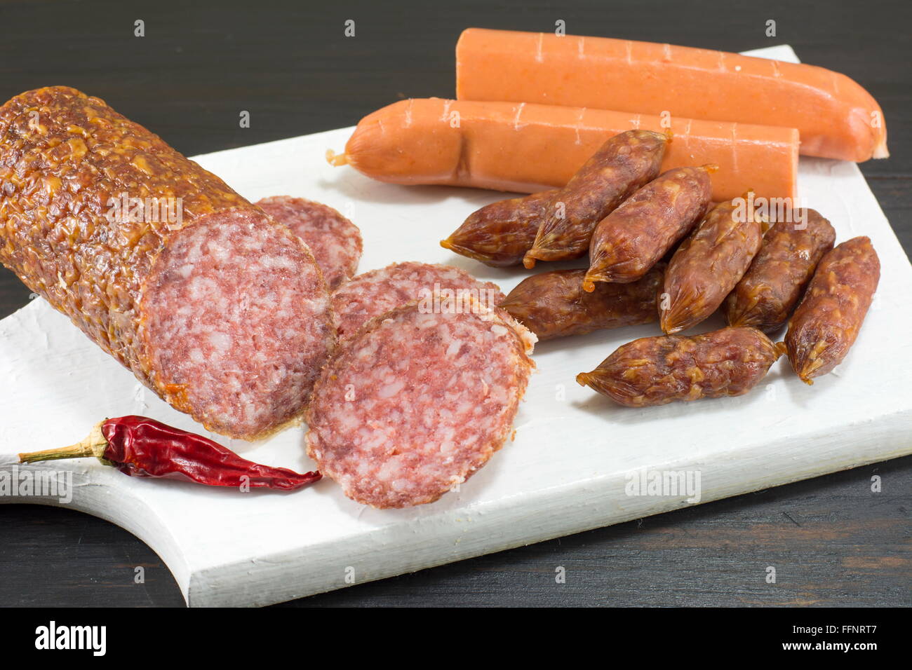 Saucisses et hot-dogs en tranches sur une planche à découper blanc Banque D'Images